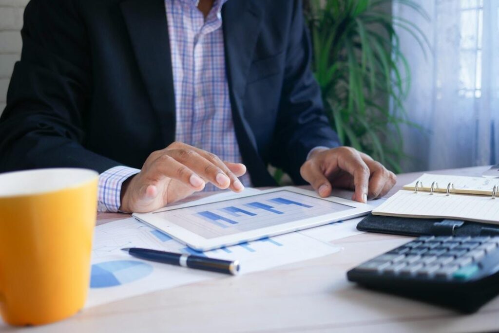 Businessman using iPad going over bar graphs to create a Marimekko chart based on the data